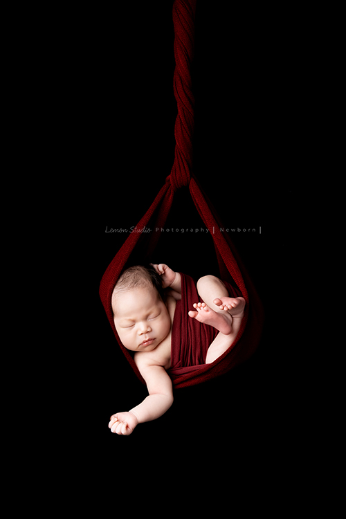 Fiamma一家第二次來拍照，這次是可愛的妹妹的新生兒寫真，這張是寶寶吊掛在紅色的布裡的新生兒寶寶寫真！非常有藝術感、特別的相片！