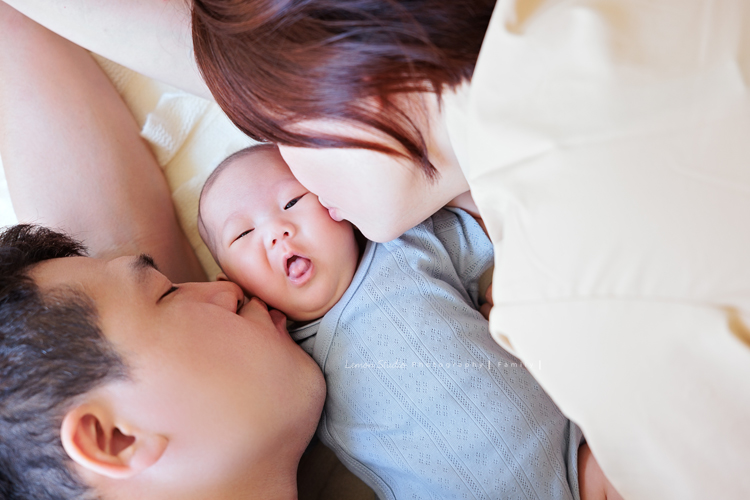 Ellie和先生帶著兩個月的寶貝及貓咪家人們來拍照，每一張相片都可以感覺到很舒服恬靜的幸福感，Eliie媽麻和先生也將平時的興趣帶入做為拍照的主題，這張是Ellie媽麻和先生親親寶貝的可愛相片！寶貝的表情好逗趣啊！