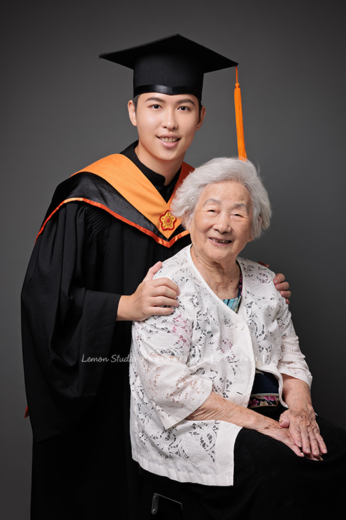 永憲和家妤碩士畢業來拍照，為要邁入人生的下一個階段做一個紀念，家人也一起入鏡拍了幾張合照，年長的奶奶也一起和孫兒拍了合照，這張是穿著碩士服的永憲和奶奶的合照！