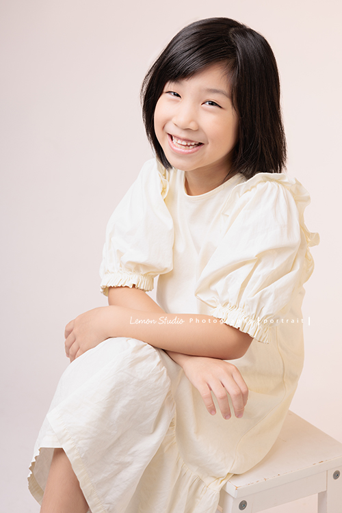 Cynthia媽麻的兩個可愛的女兒來拍寫真照，女孩們在鏡頭前很自然，拍起來不但很有質感，也抓到了兩個女孩許多不同的情緒與表情，這張是妹妹坐著看著鏡頭很有自信且笑容很可愛的個人寫真！