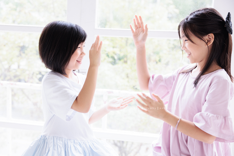 Cynthia媽麻的兩個可愛的女兒來拍寫真照，女孩們在鏡頭前很自然，拍起來不但很有質感，也抓到了兩個女孩許多不同的情緒與表情，這張是姊妹倆正玩著遊戲玩得很開心的紀錄寫真照！