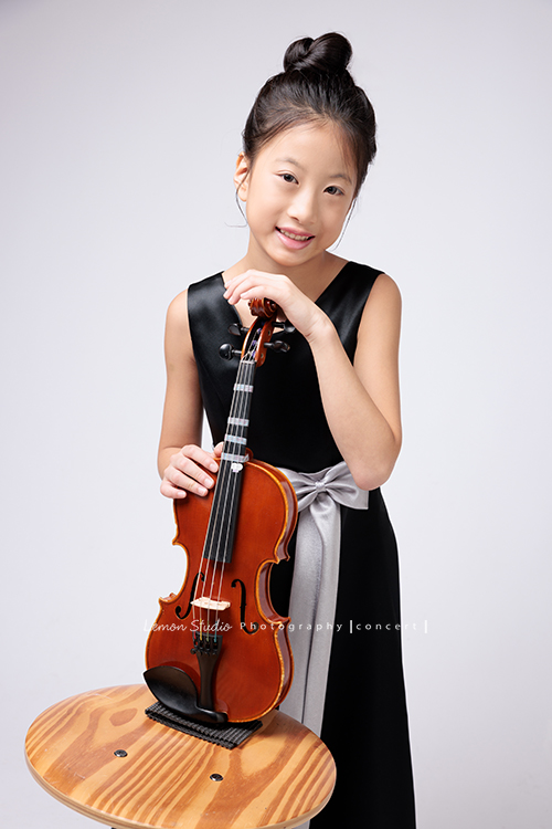 拉中提琴的晨紜和同學們這天一起來拍要辦音樂會使用的相片,這張是晨紜手扶著提琴,微笑地看著鏡頭的相片!