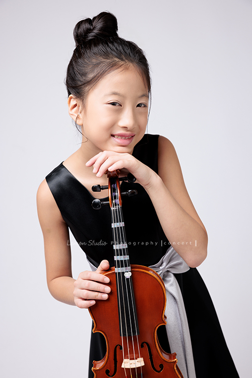 拉中提琴的晨紜和同學們這天一起來拍要辦音樂會使用的相片,這張是晨紜手扶著提琴,笑得很甜美地看著鏡頭的相片!