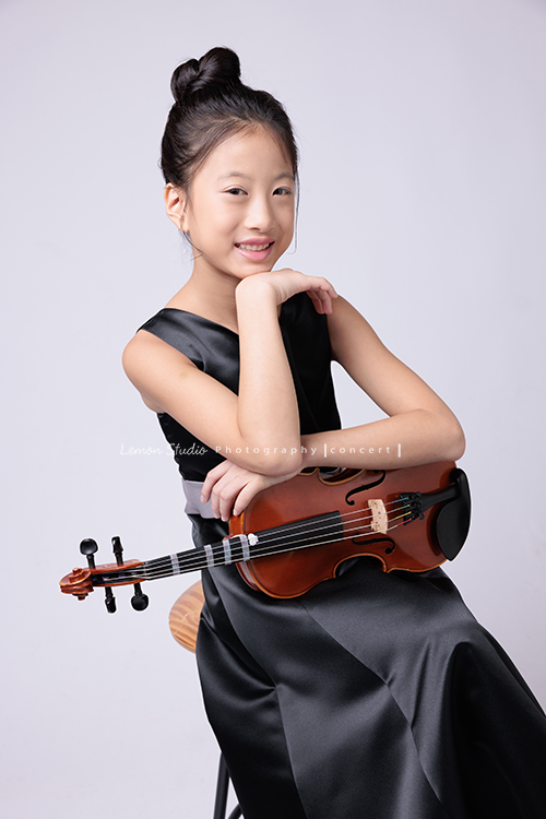 拉中提琴的晨紜和同學們這天一起來拍要辦音樂會使用的相片,這張是晨紜坐著手扶著提琴,微笑地看著鏡頭的相片!