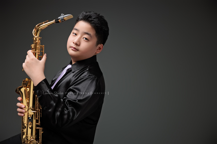 在同一個管樂團的軒＆宸兄弟檔來拍照，吹奏薩克斯風開朗的兩人，在鏡頭前很輕鬆自在地做自己，這張是弟弟宸側坐著著拿著薩克斯風酷酷地看著鏡頭的一張很帥氣的相片！