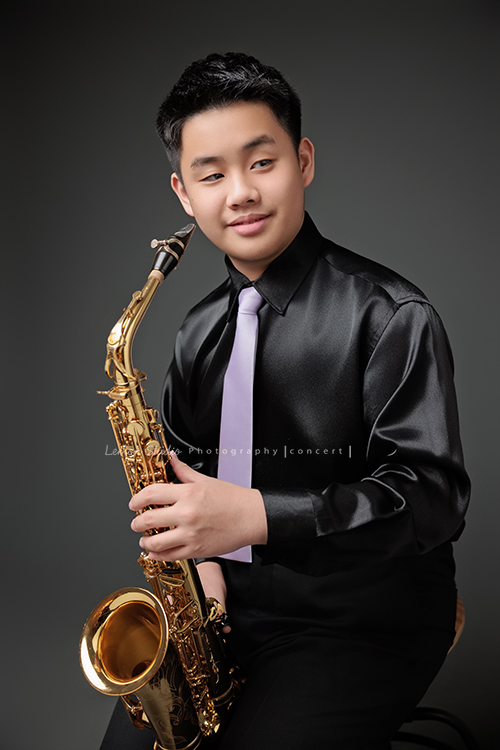 在同一個管樂團的軒＆宸兄弟檔來拍照，吹奏薩克斯風開朗的兩人，在鏡頭前很輕鬆自在地做自己，這張是哥哥軒坐著著拿著薩克斯風準備要吹奏沒有看鏡頭很有意境的一張很帥氣的相片！