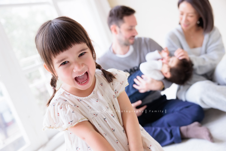 Emma媽麻一家來拍家庭寫真，四歲的姊姊琋和弟弟都是超可愛的混血兒，好喜歡這一系列相片抓到了很自然的每一個瞬間，紀錄一家的美好時刻！這張是爸拔媽麻在後面跟弟弟玩，姊姊在前面看著鏡頭笑得可愛的一瞬間紀錄！