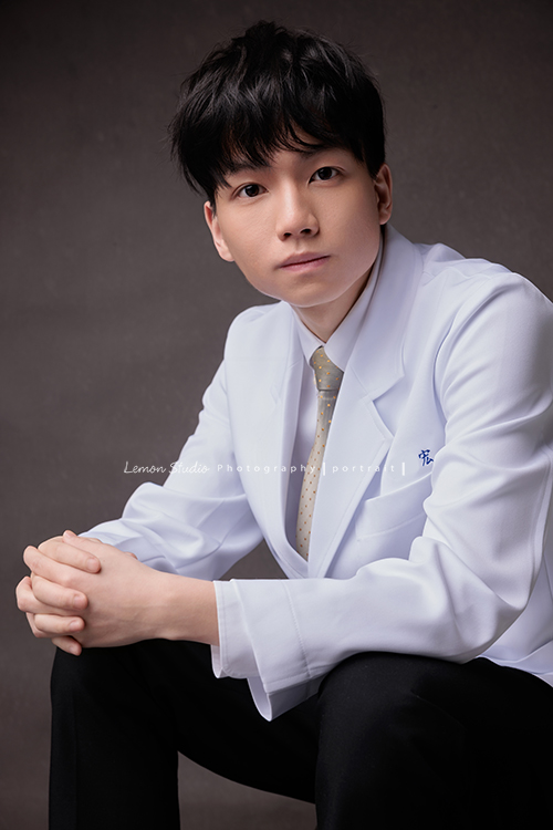 醫學院大四的宏來拍授袍紀念照，多才多藝的宏也帶了提琴入鏡，同時也把建中的制服帶來穿了拍照留念，授袍是一個很重要的里程碑，年輕又帥氣的宏這次拍照，留下了很多很棒的相片留念，這張是宏坐著看著鏡頭的一張很帥氣的授袍紀念照！