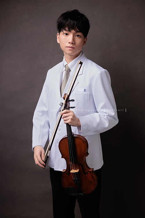 醫學院大四的宏來拍授袍紀念照，多才多藝的宏也帶了提琴入鏡，同時也把建中的制服帶來穿了拍照留念，授袍是一個很重要的里程碑，年輕又帥氣的宏這次拍照，留下了很多很棒的相片留念，這張是宏拿著提琴很沈穩地看著鏡頭的一張授袍紀念照！