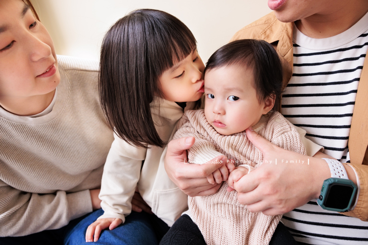 Jade媽麻一家來拍照，三歲八個月的姊姊、及八個月大的妹妹太可愛了，爸拔媽麻與姊妹倆玩得好開心，這張是爸拔媽麻抱著姊姊和妹妹，姊姊親妹妹的額頭，妹妹看著鏡頭的一張很有趣的互動相片！