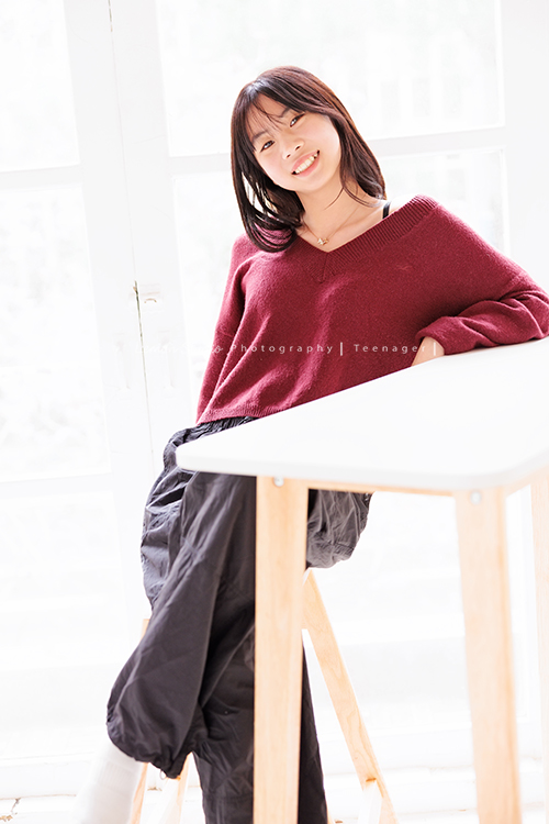 麗惠媽麻一家第四次來拍家庭寫真，第一次拍照是在15年前，當時Miranda & Charlotte都還是小小孩啊，如今姊妹倆已是美少女，這張是妹妹坐在桌子前面，看著鏡頭笑得很開心，很美的一張妹妹的個人寫真照！