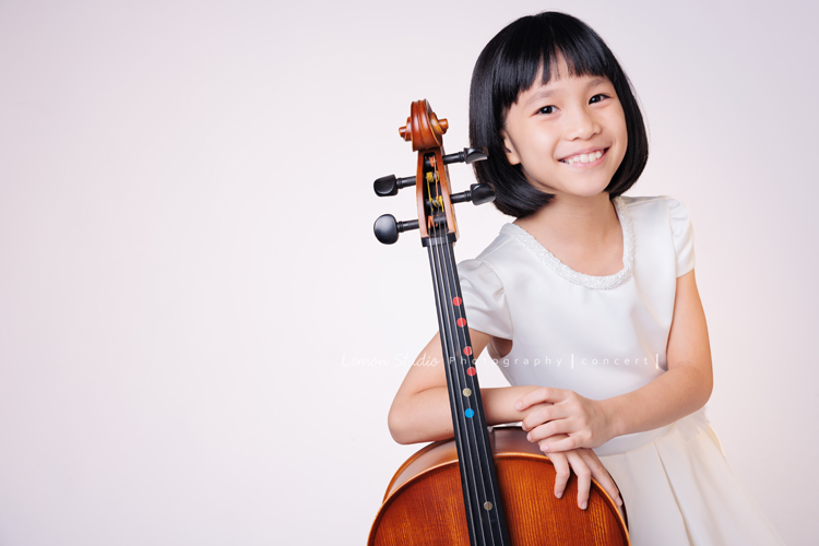 芯參加學校的弦樂團正在學習大提琴，為了即將來到的音樂會演出來拍音樂會寫真，雖然一開始拍照時有點小緊張，但逐漸地在鏡頭前越來越自在，結果捕捉到許多芯好可愛的表情及畫面，這張是芯站著手扶著大提琴很甜美地看著鏡頭笑容很燦爛的一張音樂會寫真照！