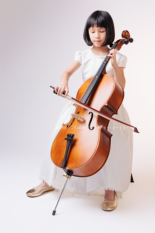 芯參加學校的弦樂團正在學習大提琴，為了即將來到的音樂會演出來拍音樂會寫真，雖然一開始拍照時有點小緊張，但逐漸地在鏡頭前越來越自在，結果捕捉到許多芯好可愛的表情及畫面，這張是芯坐著專注地拉著大提琴的一張音樂會寫真照！