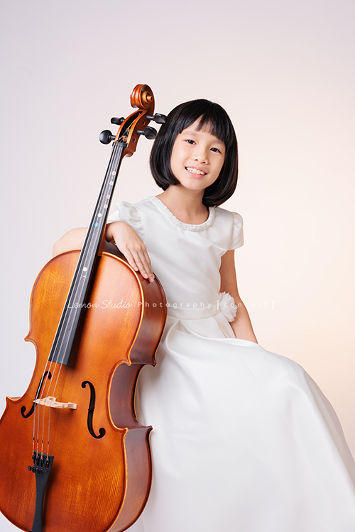 芯參加學校的弦樂團正在學習大提琴，為了即將來到的音樂會演出來拍音樂會寫真，雖然一開始拍照時有點小緊張，但逐漸地在鏡頭前越來越自在，結果捕捉到許多芯好可愛的表情及畫面，這張是芯坐著手扶在大提琴上對著鏡頭笑著的一張音樂會寫真照！