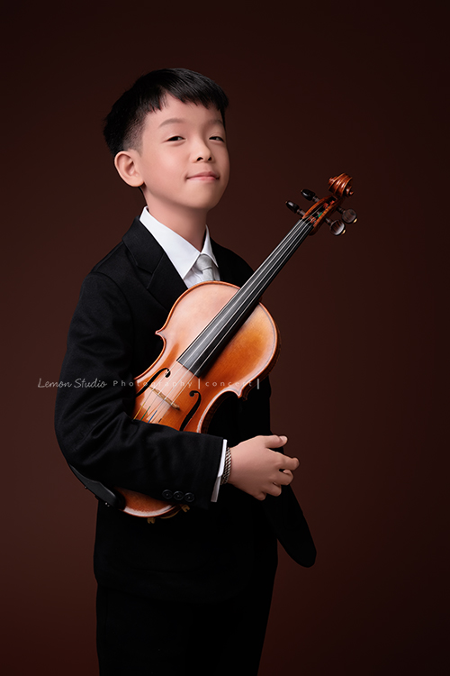 同時會拉小提琴及二胡的賢鐸來拍音樂會相片，賢鐸是學校的弦樂團A團首席及國樂全國賽特優學校二胡首席，這張是賢鐸一手抱小提琴、一手插口袋、看著鏡頭很有自信地微笑的音樂會相片！