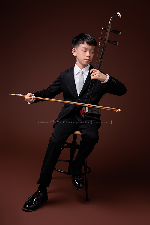 同時會拉小提琴及二胡的賢鐸來拍音樂會相片，賢鐸是學校的弦樂團A團首席及國樂全國賽特優學校二胡首席，這張是賢鐸坐在椅子上正專注地拉著二胡的的音樂會相片！