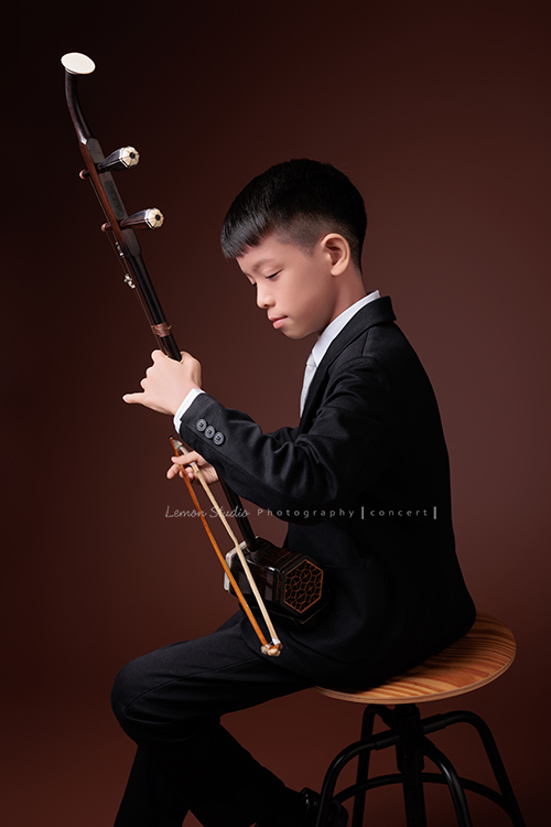同時會拉小提琴及二胡的賢鐸來拍音樂會相片，賢鐸是學校的弦樂團A團首席及國樂全國賽特優學校二胡首席，這張是賢鐸側身坐在椅子上正專注地拉著二胡的的音樂會相片！
