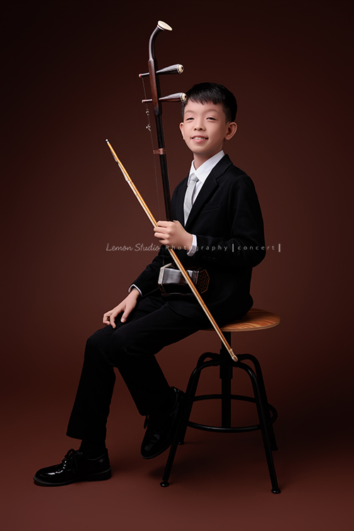 同時會拉小提琴及二胡的賢鐸來拍音樂會相片，賢鐸是學校的弦樂團A團首席及國樂全國賽特優學校二胡首席，這張是賢鐸坐在椅子上一手拿著二胡、很有自信地看著鏡頭的音樂會相片！