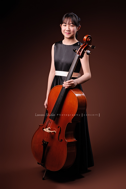 Lucie為了即將來到的音樂會帶著大提琴來拍音樂會寫真照，很有氣質的Lucie，拉琴時非常專注，Lucie笑起來很甜美，這張是Lucie站著單手扶著大提琴甜美地笑著的全身音樂寫真照！