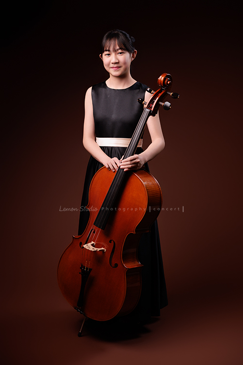 Lucie為了即將來到的音樂會帶著大提琴來拍音樂會寫真照，很有氣質的Lucie，拉琴時非常專注，Lucie笑起來很甜美，這張是Lucie站著雙手扶著大提琴甜美地笑著的全身音樂寫真照！