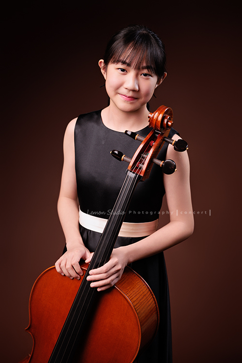 Lucie為了即將來到的音樂會帶著大提琴來拍音樂會寫真照，很有氣質的Lucie，拉琴時非常專注，Lucie笑起來很甜美，這張是Lucie站著手扶著大提琴微微地笑著的半身音樂會寫真照！