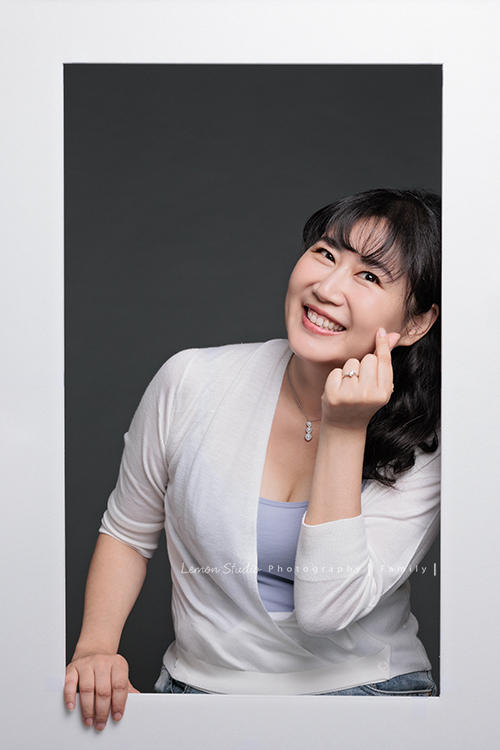 Michelle媽麻一家第二次來拍家庭寫真，這次有一些拍攝的想法與我們討論，最後請我們製作了一個很特別的無框畫，送給爺爺奶奶，爺爺奶奶收到後非常開心啊，這張是Michelle媽麻做出比愛心的動作的很可愛的一張個人照！