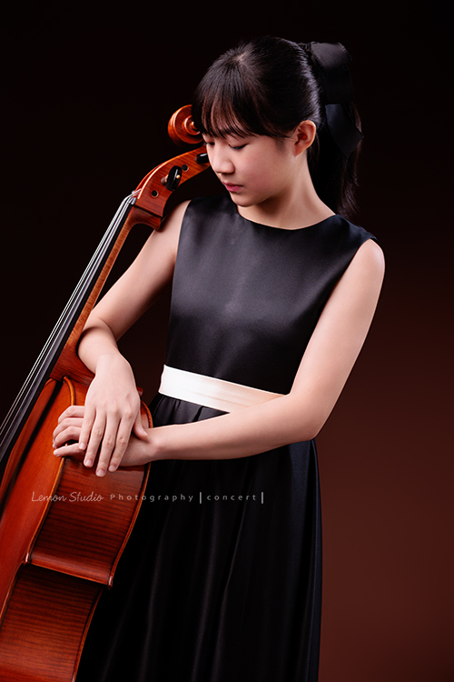 Lucie為了即將來到的音樂會帶著大提琴來拍音樂會寫真照，很有氣質的Lucie，拉琴時非常專注，Lucie笑起來很甜美，這張是Lucie站著身體靠著大提琴手輕輕扶著大提琴的七分身音樂會寫真照！Lucie低頭看著大提琴，很有意境的一張寫真照！