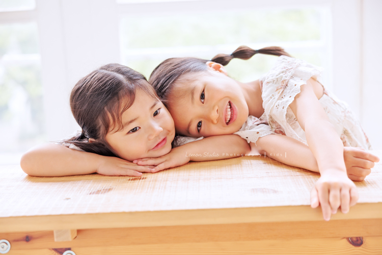 Katherine媽麻一家第三次來拍家庭寫真，這次回台灣多了第三個寶貝小妹，三姊妹在一起超可愛的，Katherine媽麻一家走自然風，喜歡很自然互動感覺的相片，我們也很喜歡啊，這張是兩位姊姊趴在椅子上互動的紀錄，大姊的頭趴在妹妹臉旁，好可愛的一張相片啊！