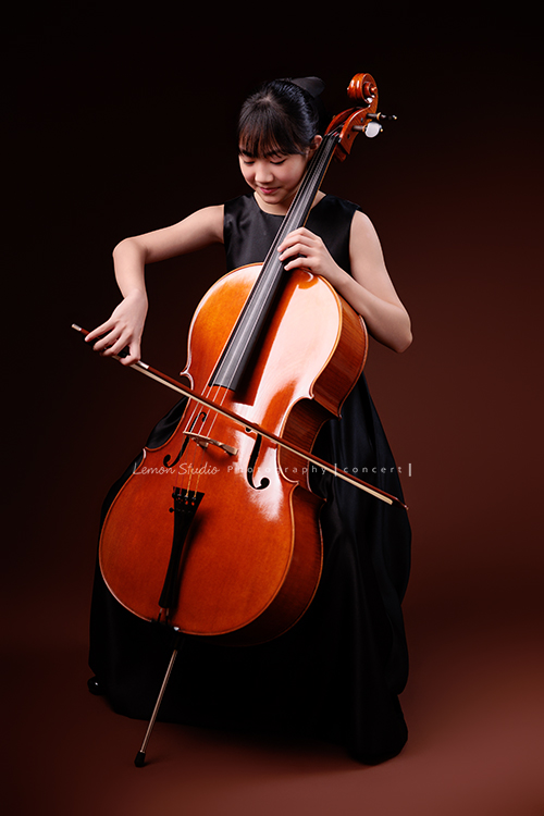 Lucie為了即將來到的音樂會帶著大提琴來拍音樂會寫真照，很有氣質的Lucie，笑起來很甜美，這張是Lucie坐在椅子上，帶著微笑正專注地拉著大提琴的模樣！