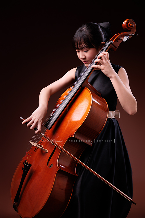 Lucie為了即將來到的音樂會帶著大提琴來拍音樂會寫真照，很有氣質的Lucie，笑起來很甜美，這張是Lucie坐在椅子上，帶著微笑正專注地拉著大提琴的側面的模樣！也是一張比較近距離的七分身的寫真！