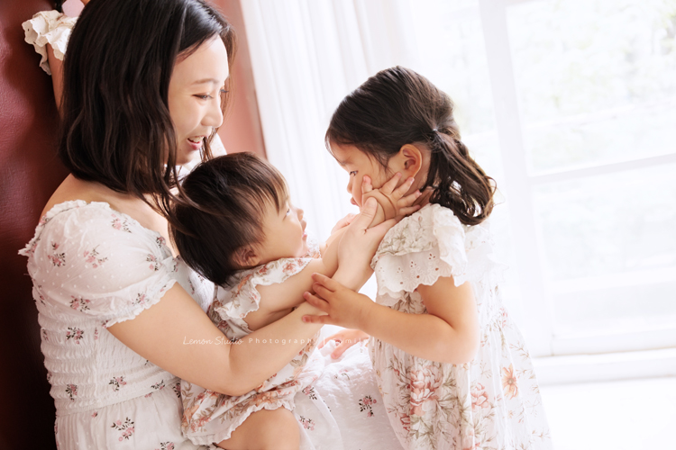 Katherine媽麻一家第三次來拍家庭寫真，這次回台灣多了第三個寶貝小妹，三姊妹在一起超可愛的，Katherine媽麻一家走自然風，喜歡很自然互動感覺的相片，我們也很喜歡啊，這張是媽麻抱著三寶玩，三寶摸著姊姊的臉，三人很可愛的互動！