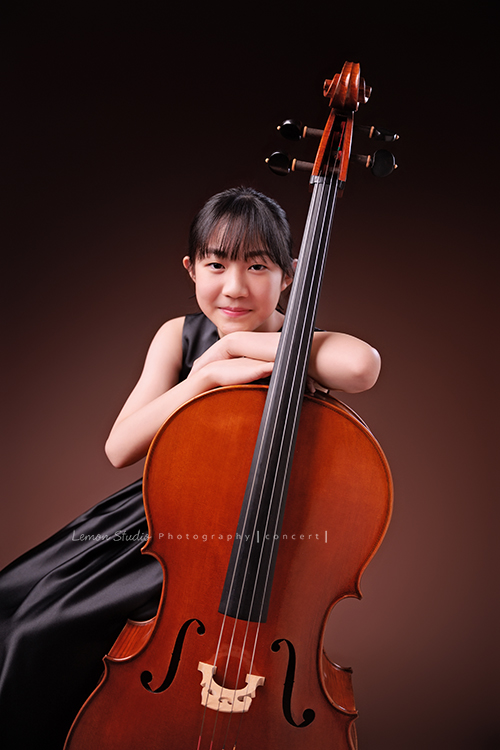 Lucie為了即將來到的音樂會帶著大提琴來拍音樂會寫真照，很有氣質的Lucie，笑起來很甜美，這張是Lucie坐在椅子上，雙手輕輕扶著大提琴，臉靠在手上，對著鏡頭甜美地微笑的模樣！