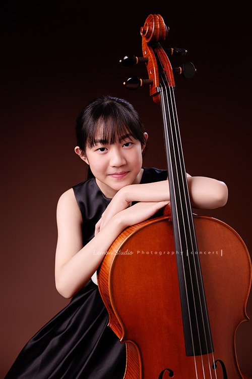 Lucie為了即將來到的音樂會帶著大提琴來拍音樂會寫真照，很有氣質的Lucie，笑起來很甜美，這張是Lucie坐在椅子上，雙手輕輕扶著大提琴，臉靠在手上，恬靜地看著鏡頭的一張很美的音樂會寫真照！