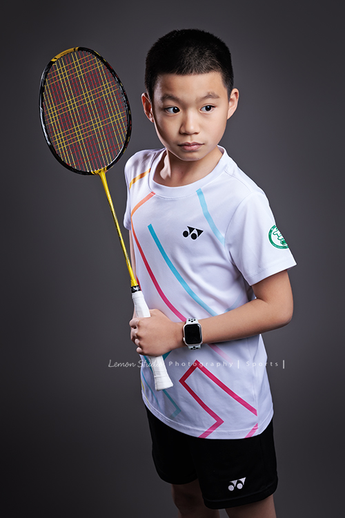這次國小羽球隊請我們拍球隊的運動寫真照，運動的孩子們有一種很專注內斂的氣質，這次還有拍孩子們打球的瞬間，好有力量好美啊，這張是羽球隊裡一位男孩的運動寫真照，男孩一手拿球拍、一手叉腰，沒有看鏡頭、表情很沈穩堅定、很帥氣！