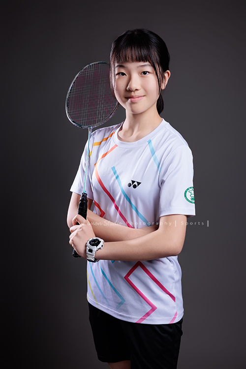 這次國小羽球隊請我們拍球隊的運動寫真照，運動的孩子們有一種很專注內斂的氣質，這次還有拍孩子們打球的瞬間，好有力量好美啊，這張是羽球隊裡一位女孩的運動寫真照，女孩一手拿著球拍、雙手環繞在前面，酷酷地很沈穩及有自信地看著鏡頭！
