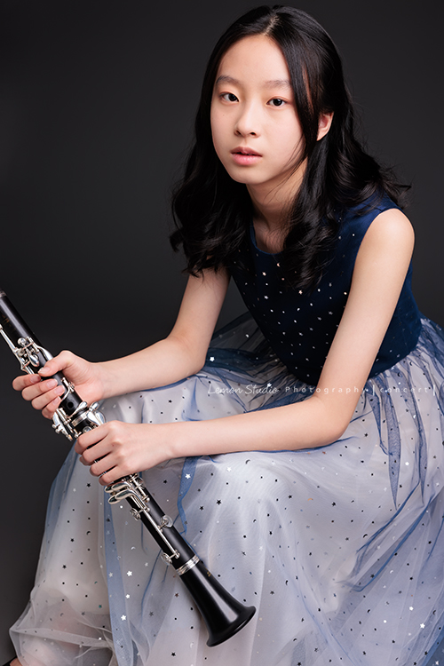 為了即將登場的音樂會，瑄帶著她的豎笛來拍攝音樂會寫真，穿上優雅的藍色系禮服，舉手投足間流露出屬於她的從容與氣質，這張是瑄坐著雙手扶拿著豎笛，帶著空靈的氣質看著鏡頭的美麗模樣！