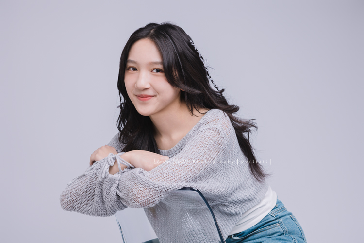 姊姊和妹妹分別來拍個人寫真，笑起來很甜美的姊姊很自在地做自己，在鏡頭前留下屬於這一刻的青春，這張是姊姊坐在椅子上、雙手扶著椅子、看著鏡頭微笑的一張的個人寫真！