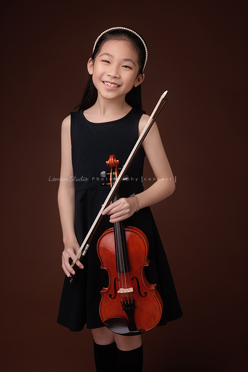 剛考上音樂班的軒，帶著她心愛的小提琴來拍音樂寫真照，一身黑色小洋裝，氣質滿滿又甜美可愛，站在鏡頭前的她個子小小的，卻閃耀著屬於自己的光芒，這一天為她的努力留下美好的紀念，這張是軒手拿著小提琴和琴弓很可愛地看著鏡頭笑得很開心的音樂寫真照！