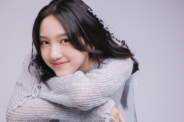 姊姊和妹妹分別來拍個人寫真，笑起來很甜美的姊姊很自在地做自己，在鏡頭前留下屬於這一刻的青春，這張是姊姊手放在椅子上、下巴靠在手上、看著鏡頭笑得很甜美的個人寫真！