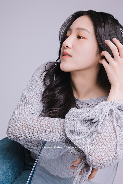 姊姊和妹妹分別來拍個人寫真，笑起來很甜美的姊姊很自在地做自己，在鏡頭前留下屬於這一刻的青春，這張是姊姊側坐在椅子上、不看鏡頭手撥著頭髮、一張很有意境的個人寫真！