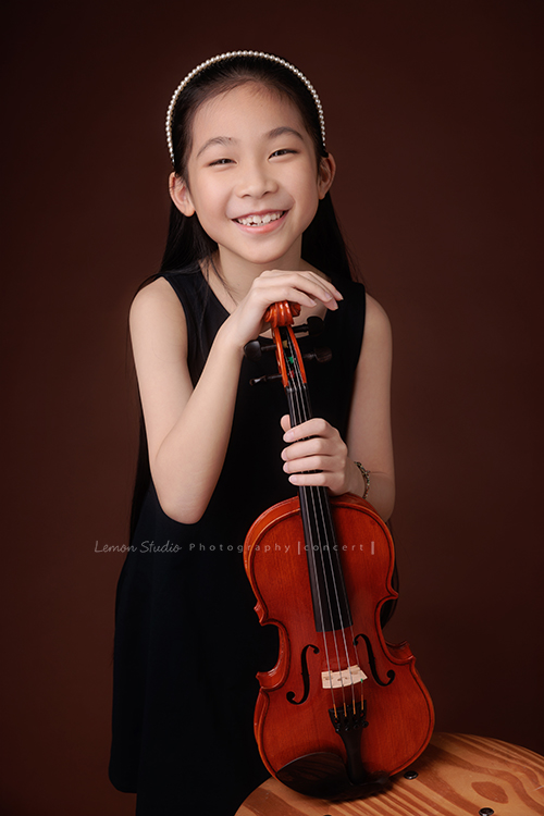 剛考上音樂班的軒，帶著她心愛的小提琴來拍音樂寫真照，一身黑色小洋裝，氣質滿滿又甜美可愛，站在鏡頭前的她個子小小的，卻閃耀著屬於自己的光芒，這一天為她的努力留下美好的紀念，這張是軒雙手扶著小提琴看著鏡頭笑得很燦爛的音樂寫真照！