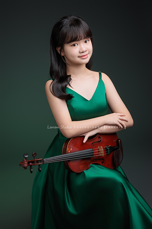 安在音樂班畢業前來拍音樂會要使用的相片，穿了一襲很美的綠色禮服，主修小提琴的安笑起來很甜美，這張是安坐著雙手放在小提琴上，很甜美地對著鏡頭微笑的音樂會相片！