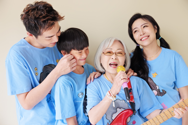 小妃媽麻一家帶著外婆來拍家庭攝影，外婆本來在鏡頭前有點靦腆，後來開始唱起歌來欲罷不能，一家人和外婆感情超好，在鏡頭前活潑且自然，這張是一家三口和外婆很有趣的一張互動紀錄！外婆正在唱歌、爸拔親親地捏著孩子的臉、一家人陪著外婆唱歌很可愛的互動紀錄！