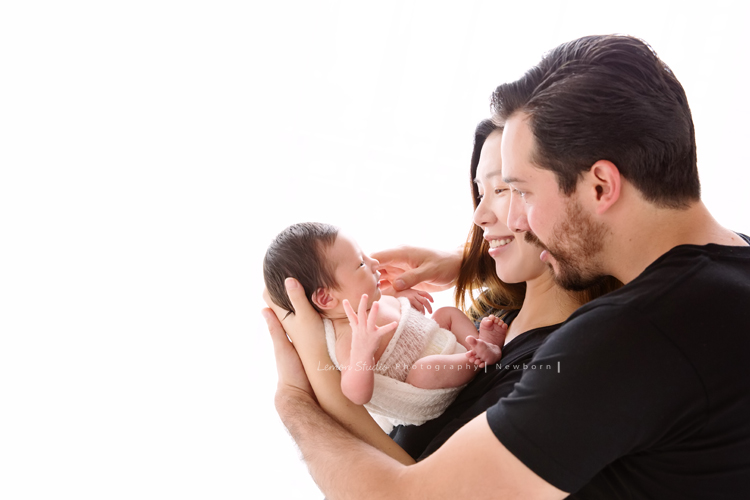 Diana媽麻和先生帶著剛出生的寶寶來拍新生兒攝影，外國人的爸拔和媽麻一起抱著寶寶，三人之間的互動自然又真摯，這是他們第一次的全家福，也是送給寶寶最有溫度美好的出生禮物，這張是爸拔媽麻將寶寶抱在他們兩人的前方，兩人充滿愛地看著寶寶的幸福模樣！