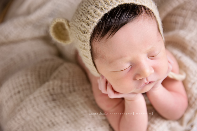 Diana媽麻和先生帶著剛出生的寶寶來拍新生兒攝影，外國人的爸拔和媽麻一起抱著寶寶，三人之間的互動自然又真摯，這是他們第一次的全家福，也是送給寶寶最有溫度美好的出生禮物，這張是寶寶穿著道具服雙手托著頭睡著的可愛模樣，這張是比較近的近拍！