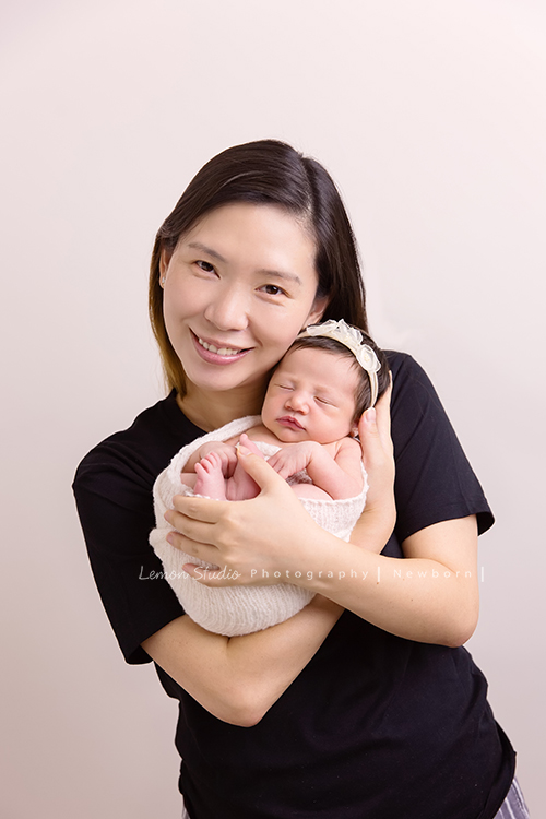 Diana媽麻和先生帶著剛出生的寶寶來拍新生兒攝影，外國人的爸拔和媽麻一起抱著寶寶，三人之間的互動自然又真摯，這是他們第一次的全家福，也是送給寶寶最有溫度美好的出生禮物，這張是媽麻將寶寶抱在前方，媽麻充滿愛地抱著寶寶看著鏡頭微笑的幸福模樣！