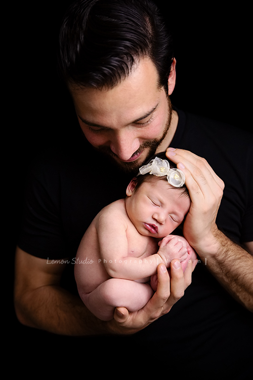 Diana媽麻和先生帶著剛出生的寶寶來拍新生兒攝影，外國人的爸拔和媽麻一起抱著寶寶，三人之間的互動自然又真摯，這是他們第一次的全家福，也是送給寶寶最有溫度美好的出生禮物，這張是爸拔將寶寶抱在胸前、看著寶寶微笑的幸福模樣！