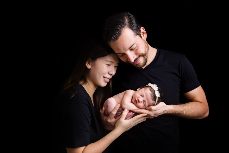 Diana媽麻和先生帶著剛出生的寶寶來拍新生兒攝影，外國人的爸拔和媽麻一起抱著寶寶，三人之間的互動自然又真摯，這是他們第一次的全家福，也是送給寶寶最有溫度美好的出生禮物，這張是爸拔媽麻將寶寶抱在他們兩人的前方，兩人充滿愛地抱著寶寶的幸福模樣！