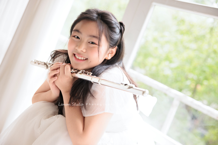 宥欣自小喜愛長笛，樂於在台上演出並與大家分享美好的音樂，9歲時即以非凡的音樂表現脫穎而出，成為台灣歷年來長笛組最年輕首位榮獲日本第33回古典音樂大賽全國大會總決賽長笛部國小中年級最高名次，今年剛滿11歲的她，將於11月底舉辦人生中的第一場獨奏會，有興趣的人可以留言跟我們索票喔，這張是宥欣穿著白色禮服雙手拿著長笛，頭輕輕靠在長笛上，看著鏡頭笑得很甜美的一張長笛音樂寫真！