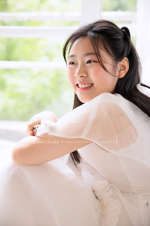 宥欣自小喜愛長笛，樂於在台上演出並與大家分享美好的音樂，9歲時即以非凡的音樂表現脫穎而出，成為台灣歷年來長笛組最年輕首位榮獲日本第33回古典音樂大賽全國大會總決賽長笛部國小中年級最高名次，今年剛滿11歲的她，將於11月底舉辦人生中的第一場獨奏會，有興趣的人可以留言跟我們索票喔，這張是宥欣穿著白色禮服手拿著長笛，沒有看鏡頭看向側面，笑得很甜美，很有意境的一張長笛音樂寫真！